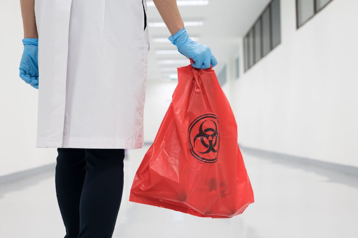 woman holding a red biohazard waste bag
